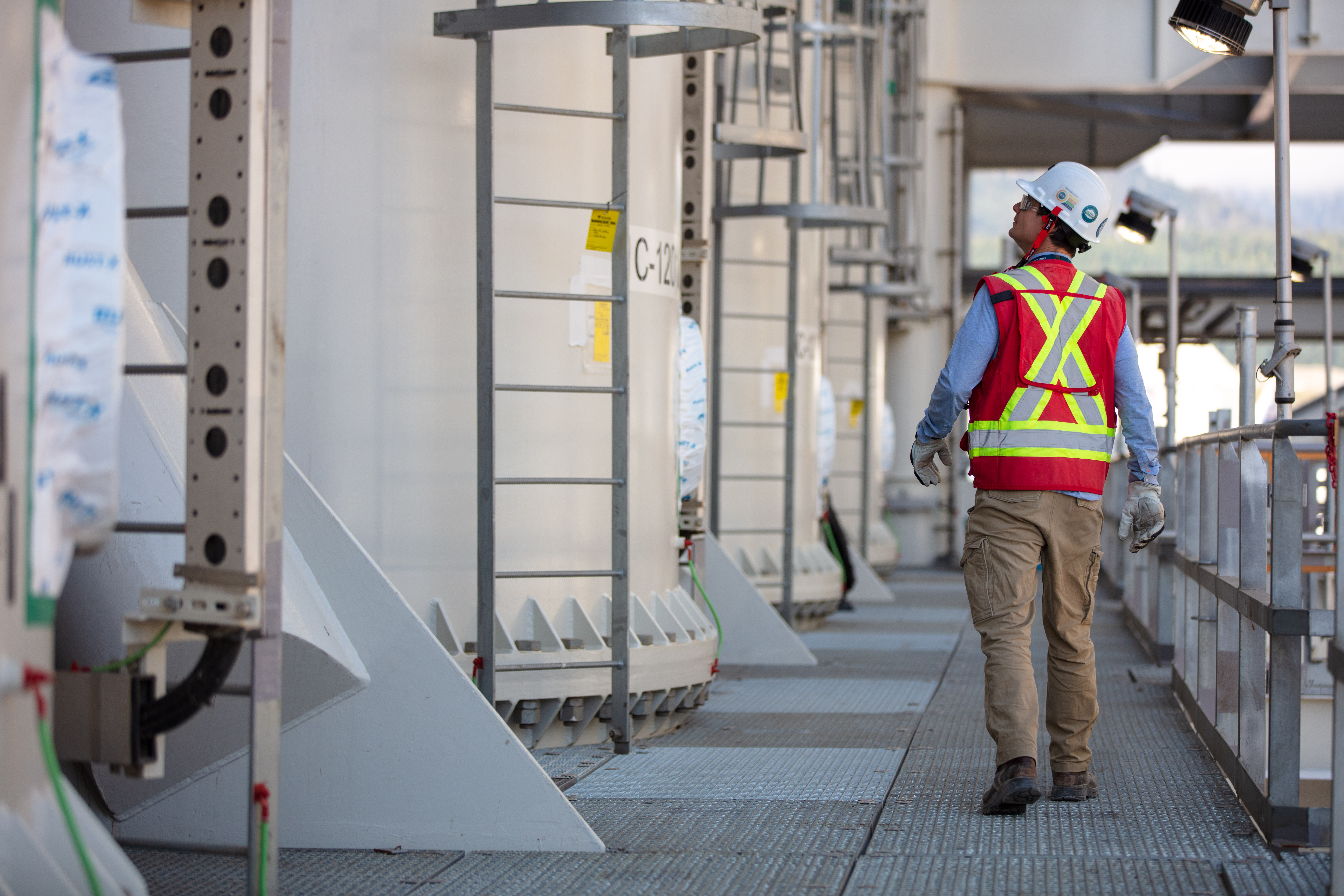 Skilled worker inspecting industrial operational infrastructure at the LNG Canada site in Kitimat, British Columbia