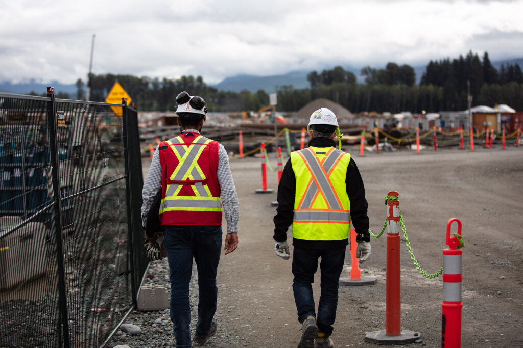 Back view of two construction workers walking on the construction site