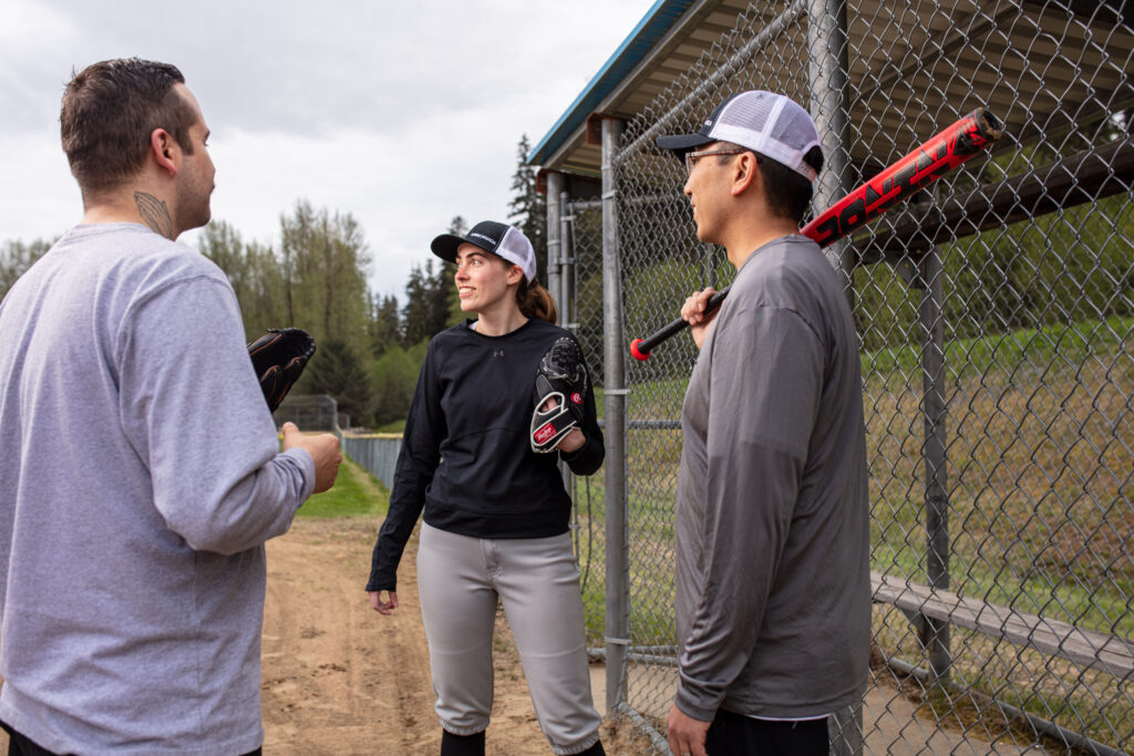 Three individuals enjoying a game of baseball, chatting on the sidelines of the field