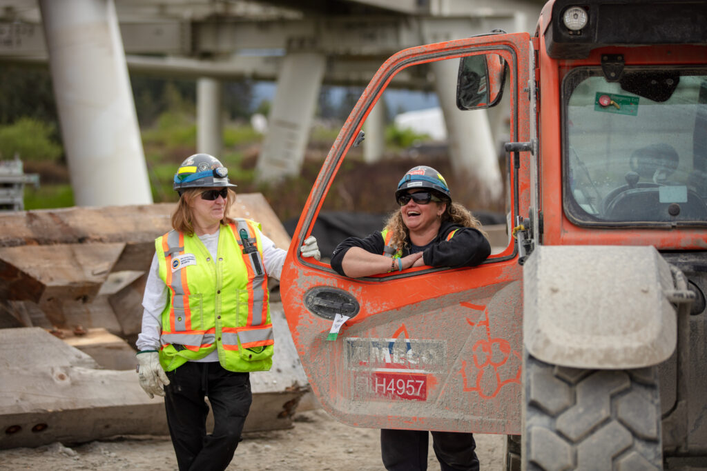 Two female construction workers chatting and sharing a laugh at a construction site